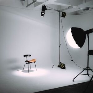 Empty photography studio with lighting equipment focused on a single chair.